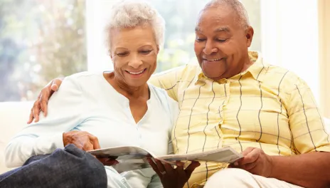 older adult couple reading magazine on couch