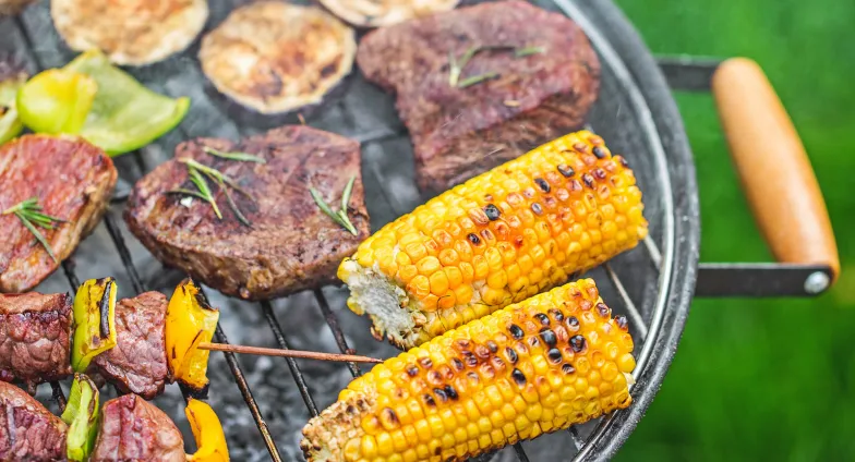 charcoal grill with corn on the cob, kabobs and steak 