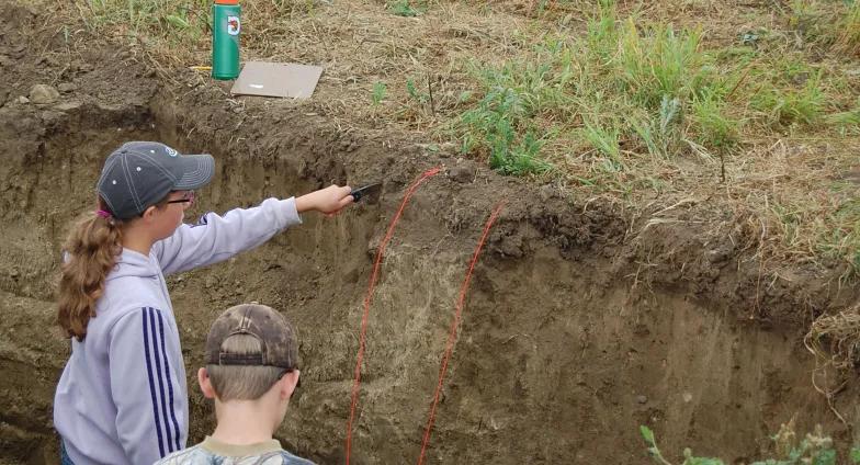 two youth identifying layers of soil in land judging competition